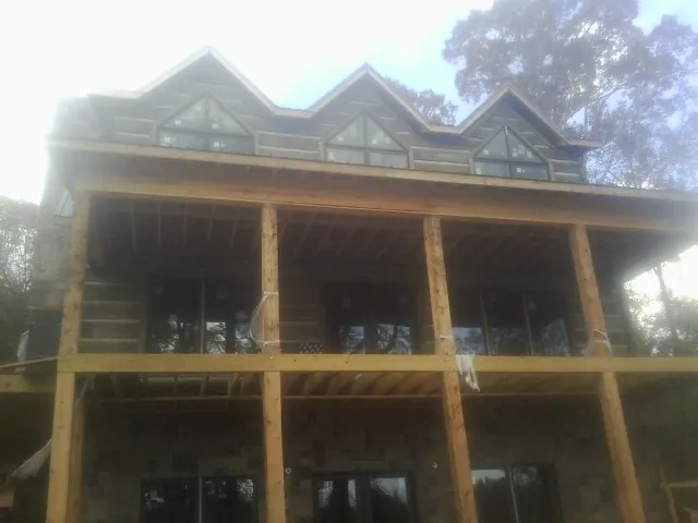 Dormers and porch framing on a large log home under construction — Roof Coating work by our crew in De Witt