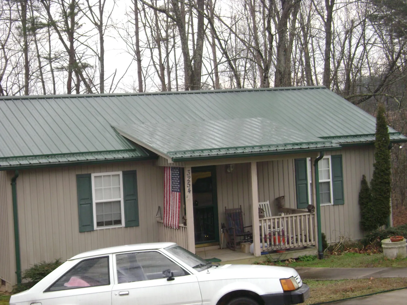 Green metal roof and front porch on a tan sided cottage in De Witt